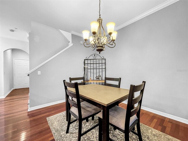 dining area featuring dark hardwood / wood-style floors, crown molding, and a notable chandelier