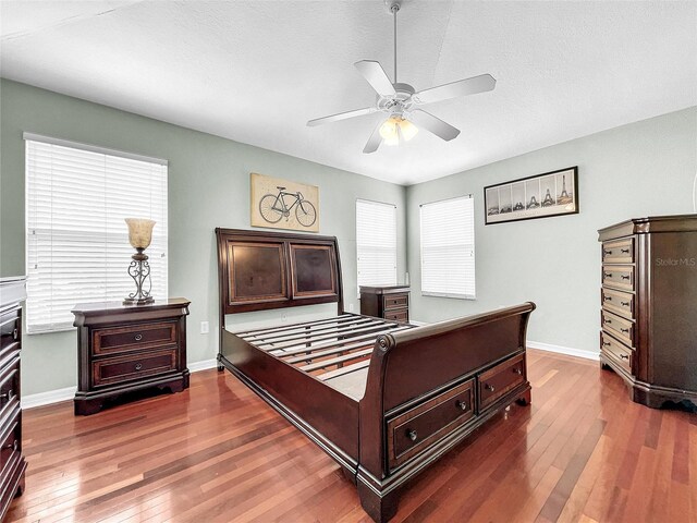 bedroom with hardwood / wood-style floors, ceiling fan, and multiple windows