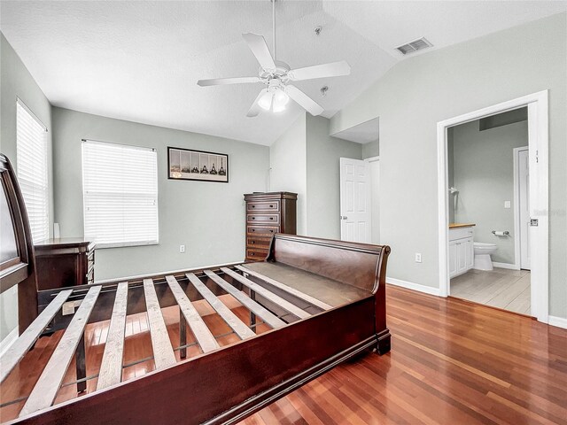 bedroom with wood-type flooring, connected bathroom, vaulted ceiling, and ceiling fan