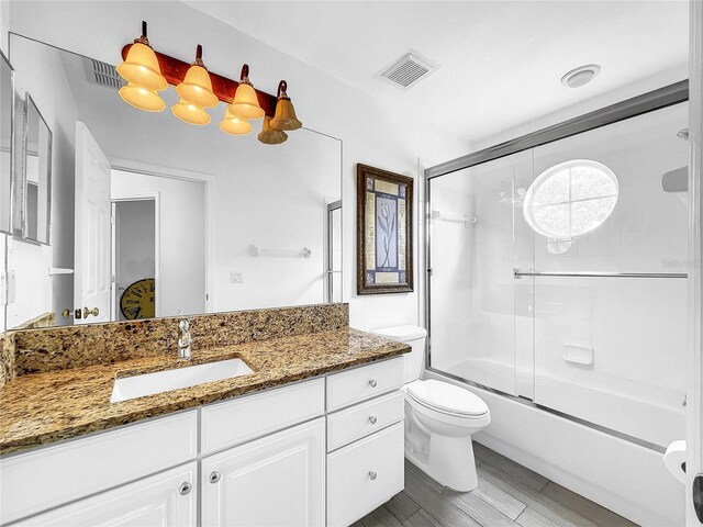 full bathroom with toilet, vanity, bath / shower combo with glass door, and hardwood / wood-style flooring