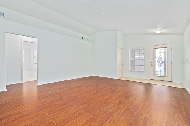 unfurnished living room featuring lofted ceiling and light wood-type flooring