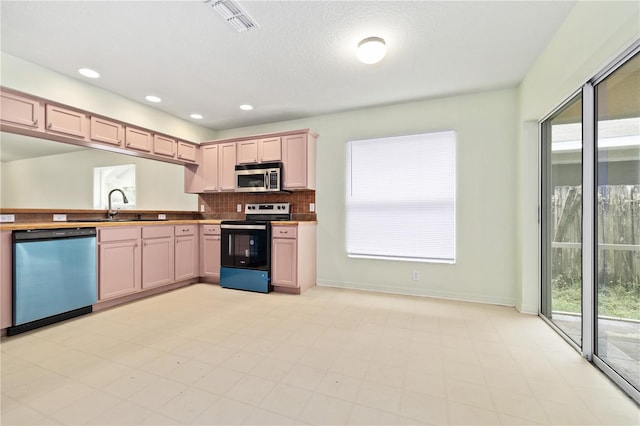 kitchen featuring backsplash, sink, light brown cabinetry, and appliances with stainless steel finishes