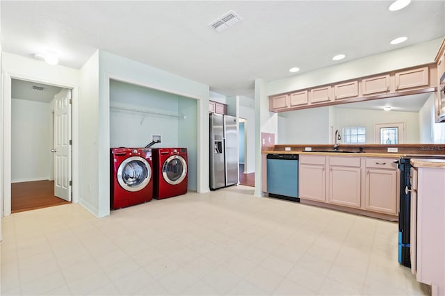 kitchen with light brown cabinetry, sink, washer and dryer, and appliances with stainless steel finishes