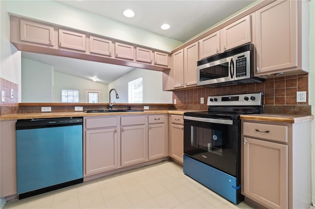 kitchen with tasteful backsplash, sink, lofted ceiling, and appliances with stainless steel finishes