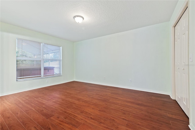 spare room featuring dark hardwood / wood-style flooring and a textured ceiling