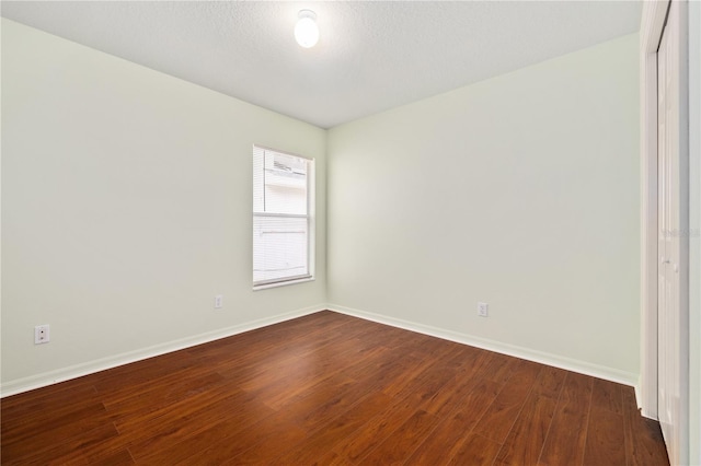 unfurnished room featuring a textured ceiling and dark hardwood / wood-style floors