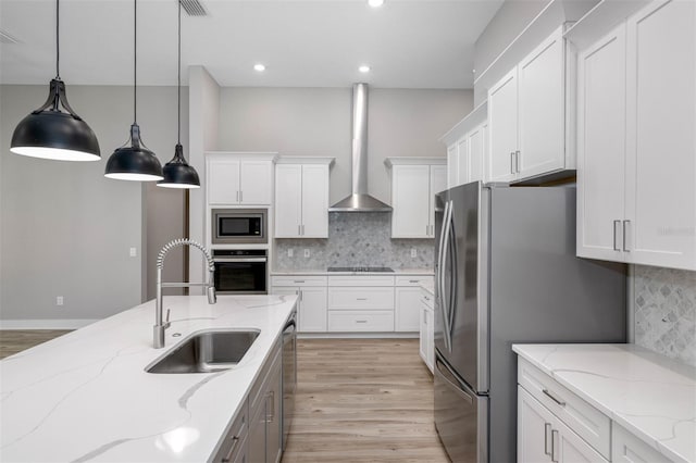 17059 Nokota Ave, Hudson, FL 34667 - kitchen featuring appliances with stainless steel finishes, wall chimney range hood, white cabinets, light wood-style floors, and recessed lighting