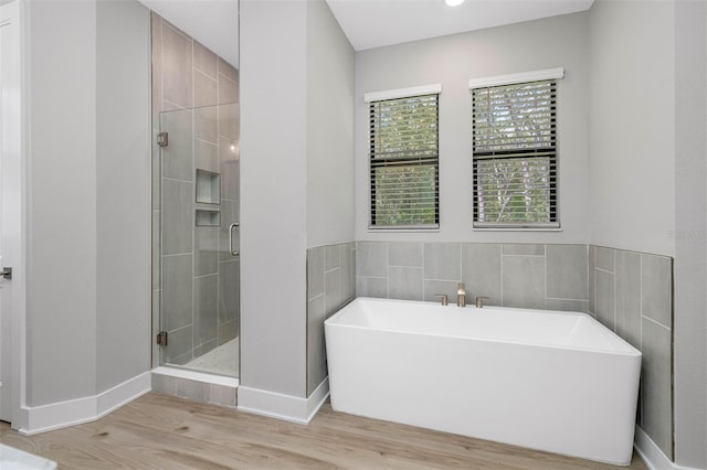 bathroom featuring wood-type flooring and shower with separate bathtub