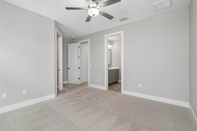 unfurnished bedroom with ensuite bathroom, ceiling fan, and light colored carpet