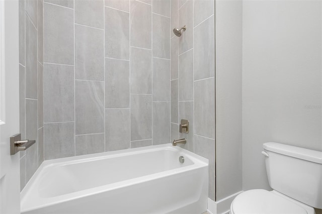 bathroom featuring toilet and tiled shower / bath