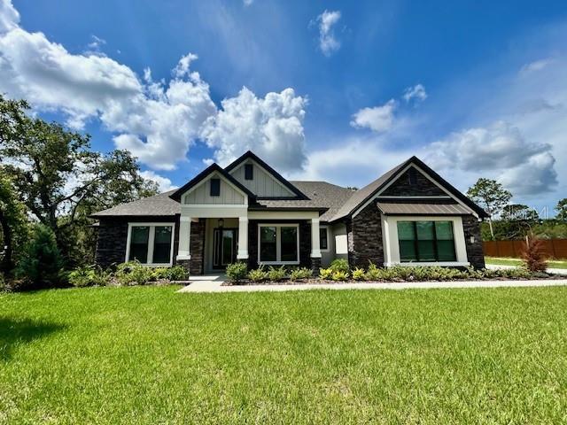 17059 Nokota Ave, Hudson, FL 34667 - craftsman-style home with stone siding and a front lawn