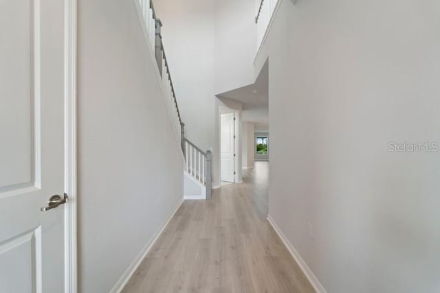 hallway featuring light wood-type flooring and a high ceiling