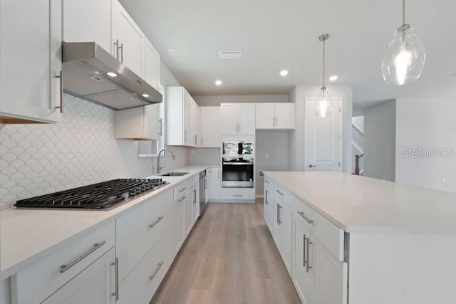 kitchen featuring sink, hanging light fixtures, backsplash, light hardwood / wood-style floors, and white cabinets