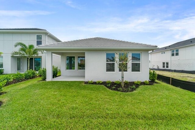 rear view of house with a patio and a lawn