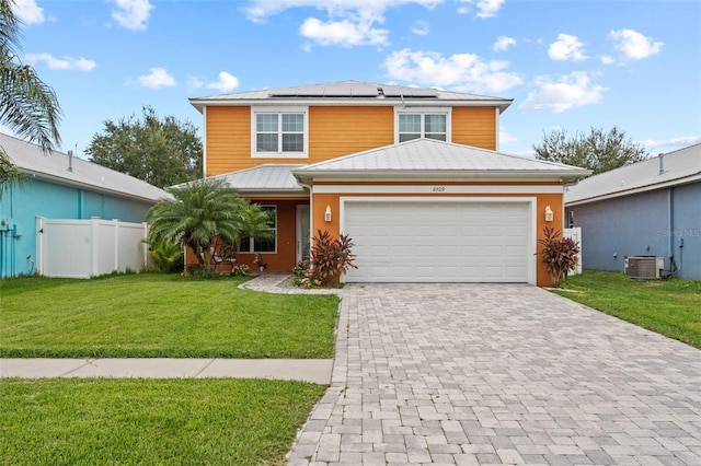 front of property featuring a garage, a front lawn, solar panels, and central AC