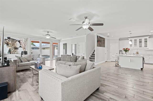 living room with crown molding, light hardwood / wood-style flooring, and ceiling fan