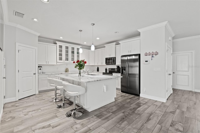 kitchen with white cabinets, light stone countertops, stainless steel appliances, sink, and a center island with sink