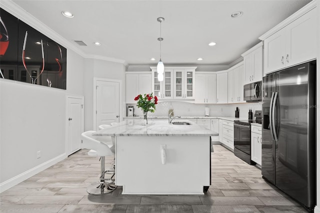 kitchen featuring a kitchen island with sink, white cabinetry, light stone counters, appliances with stainless steel finishes, and a breakfast bar area