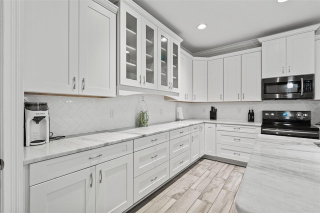 kitchen featuring white cabinetry, light hardwood / wood-style flooring, tasteful backsplash, stainless steel appliances, and light stone counters