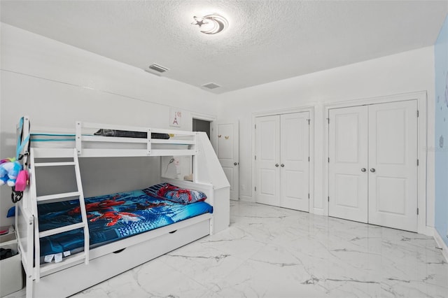 bedroom featuring a textured ceiling and multiple closets