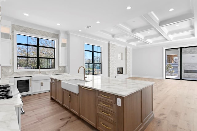 kitchen featuring white cabinetry, light stone countertops, sink, and wine cooler