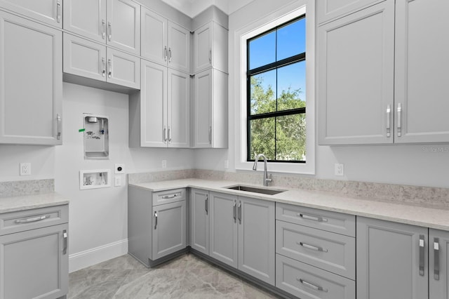 kitchen with sink, gray cabinets, and light stone countertops