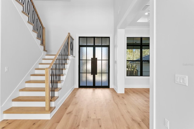 foyer entrance with a towering ceiling, light hardwood / wood-style floors, and french doors