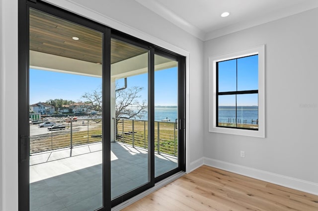 doorway to outside with light hardwood / wood-style flooring and a water view