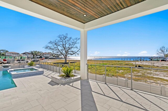 view of patio / terrace with a water view, a balcony, and an in ground hot tub