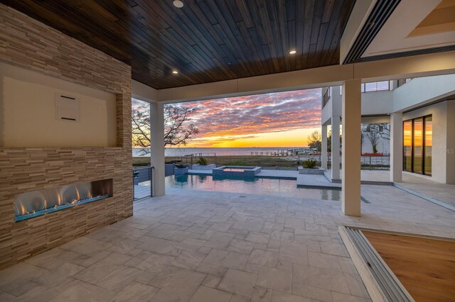 patio terrace at dusk featuring an outdoor kitchen and a pool with hot tub