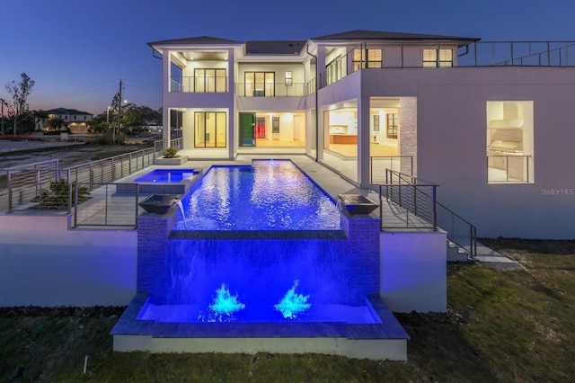 rear view of house with a pool with hot tub, a patio area, pool water feature, and a balcony