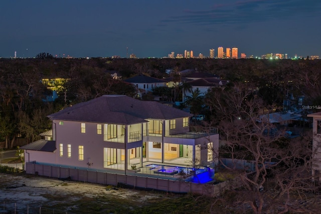back house at night featuring a patio area and a balcony