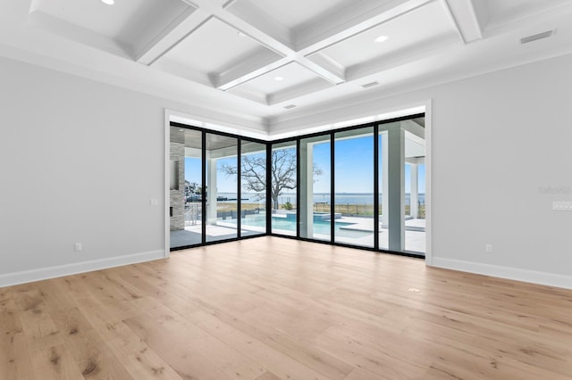 spare room featuring beam ceiling, coffered ceiling, and light wood-type flooring