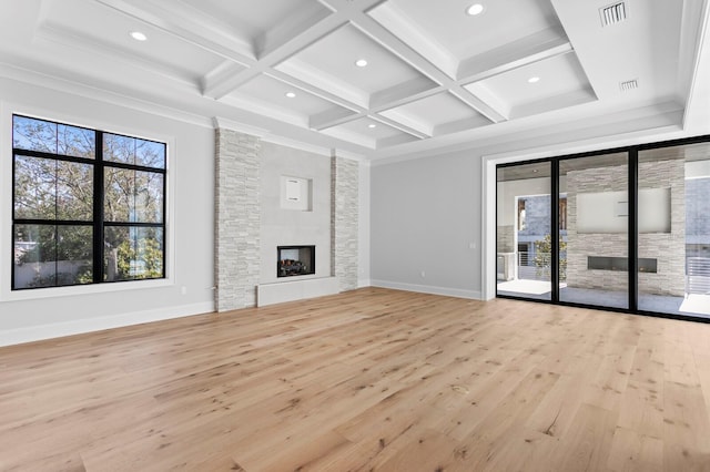 unfurnished living room featuring coffered ceiling, a stone fireplace, crown molding, light wood-type flooring, and beamed ceiling