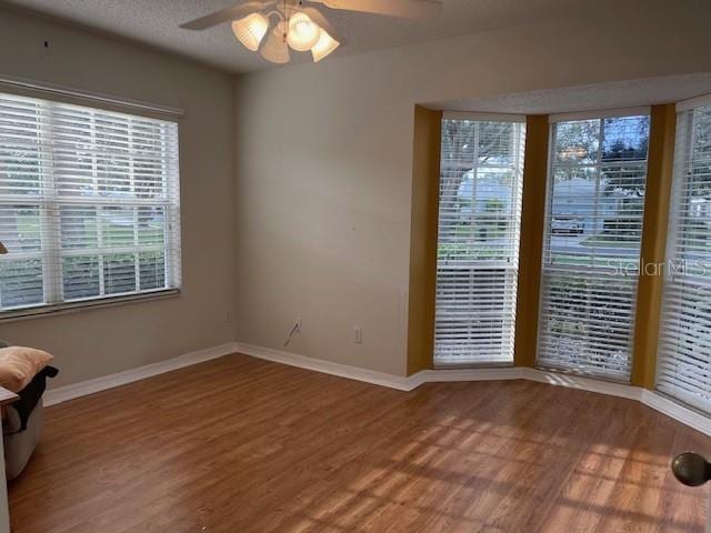 empty room with ceiling fan, wood-type flooring, and a textured ceiling