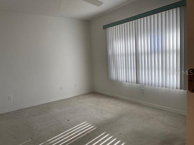 spare room with carpet flooring, ceiling fan, and baseboards