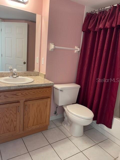 full bathroom with toilet, vanity, shower / tub combo with curtain, and tile patterned flooring