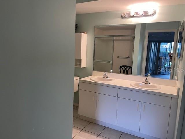 bathroom with toilet, vanity, an enclosed shower, and tile patterned flooring