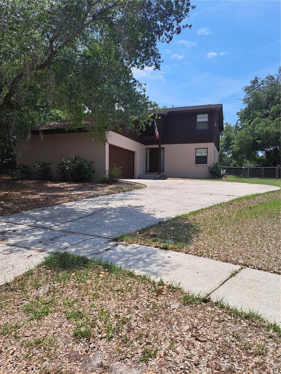 view of front facade featuring concrete driveway, an attached garage, and fence