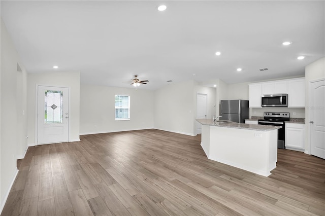 kitchen with white cabinetry, appliances with stainless steel finishes, light hardwood / wood-style floors, and an island with sink