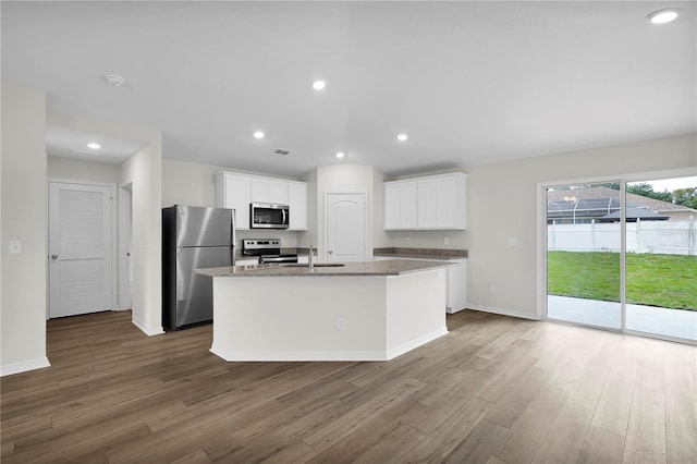 kitchen with stainless steel appliances, an island with sink, dark hardwood / wood-style flooring, and white cabinetry