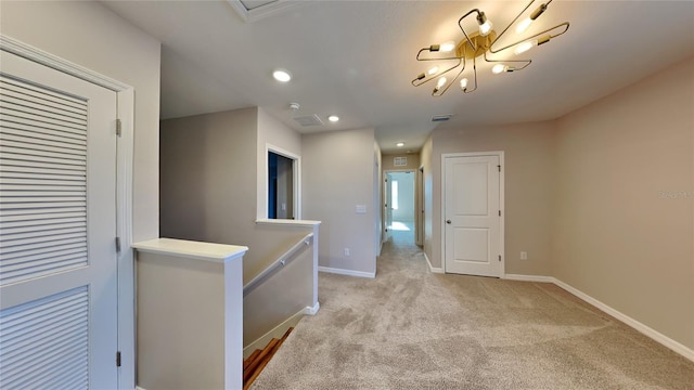 hallway with light carpet and a notable chandelier