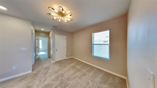 unfurnished room with light carpet and a notable chandelier