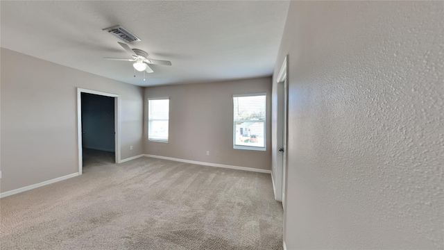 empty room with ceiling fan and light carpet