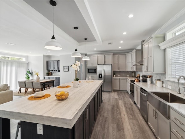 kitchen featuring hanging light fixtures, gray cabinets, tasteful backsplash, a kitchen island, and stainless steel appliances