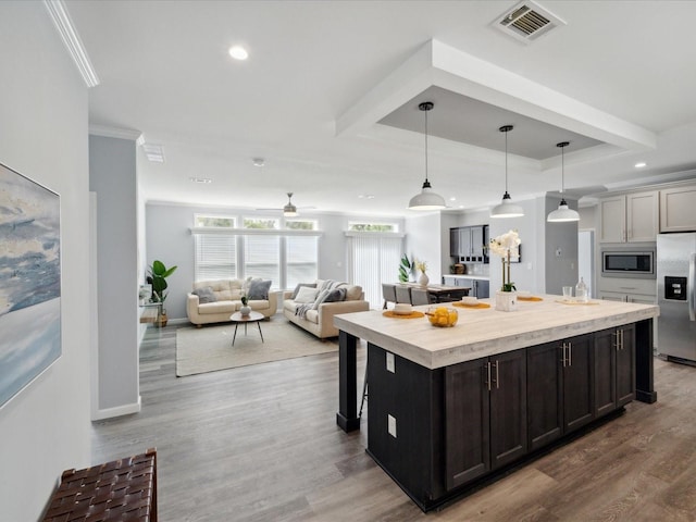 kitchen with pendant lighting, hardwood / wood-style flooring, ceiling fan, appliances with stainless steel finishes, and a kitchen island