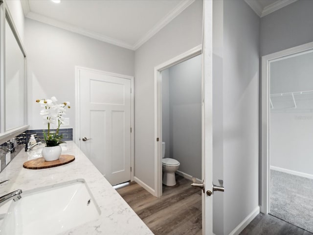 bathroom featuring vanity, toilet, wood-type flooring, and crown molding