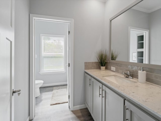 bathroom featuring vanity, toilet, crown molding, and tasteful backsplash