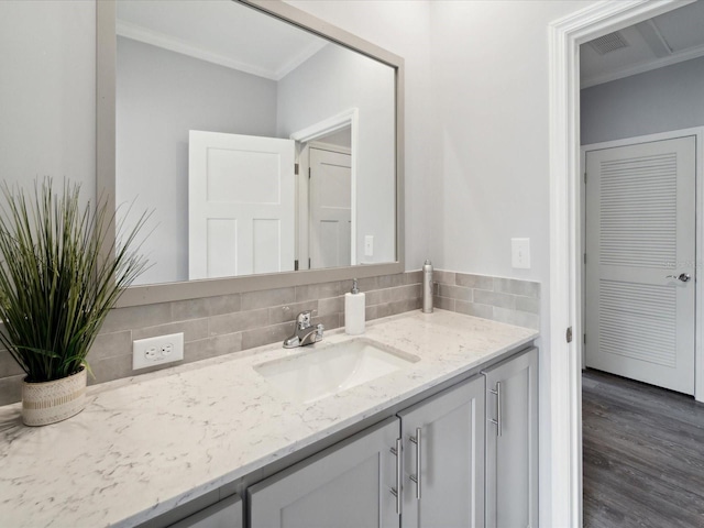 bathroom with vanity, wood-type flooring, ornamental molding, and tasteful backsplash