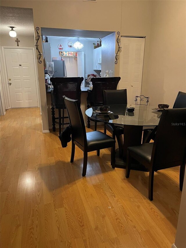 dining area featuring light hardwood / wood-style floors and a textured ceiling